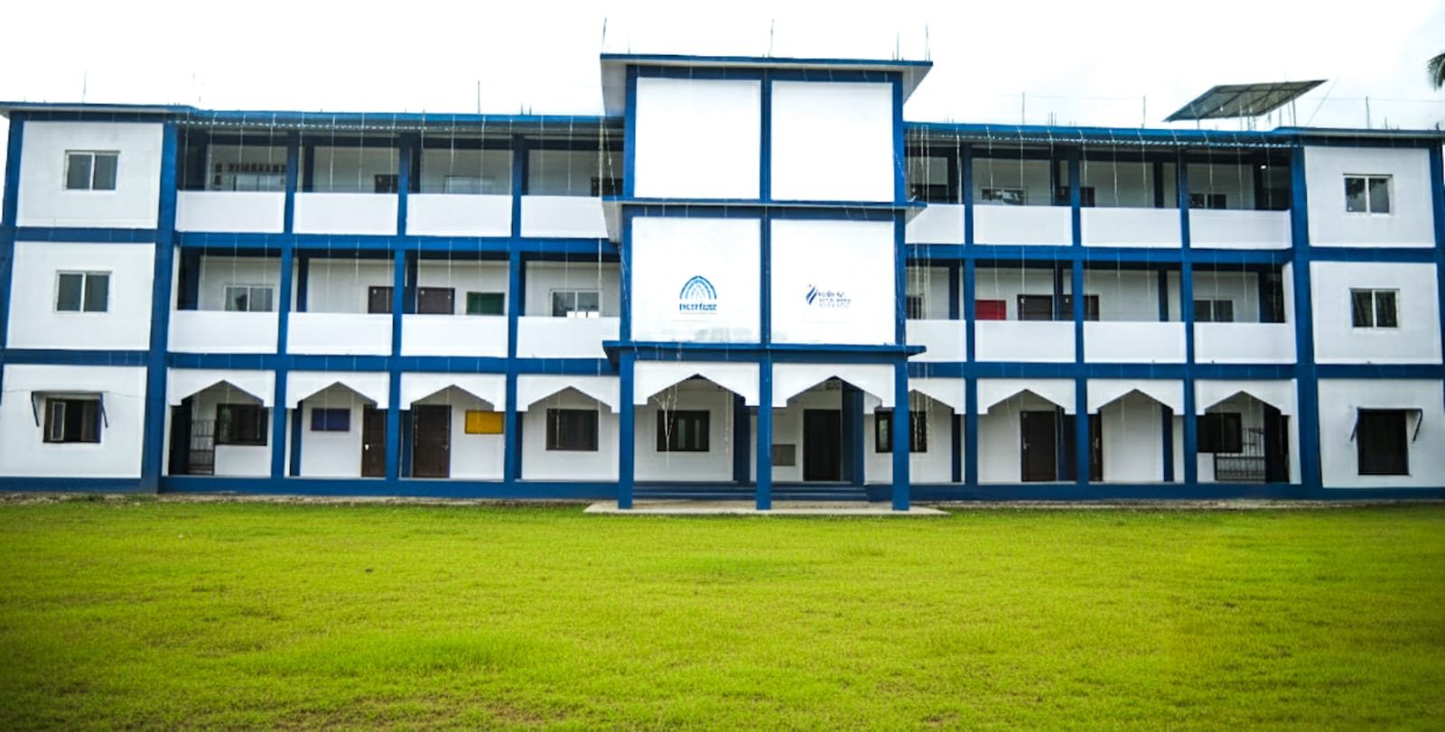 The three-storey Markaz Public School building in white and blue, with a green lawn in front